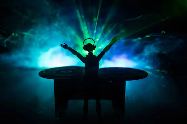 Concepto de club de DJ. Mujer mezclando DJ, y rascándose en un club nocturno. Silueta de niña en la cubierta de DJ, luces estroboscópicas y niebla en el fondo. Decoración creativa de obras de arte con juguete . —  Fotos de Stock