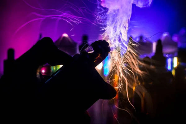 Concepto Vape. Explosión electrónica de vapores de cigarrillos. Nubes de humo y botellas de vapor líquido sobre fondo oscuro. Efectos de luz. Útil como anuncio de vapor . — Foto de Stock