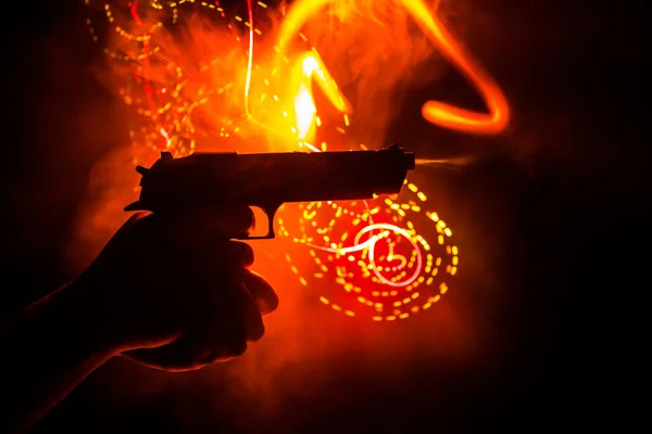 Pistola de mano masculina sobre fondo negro con luces traseras tonificadas con humo — Foto de Stock