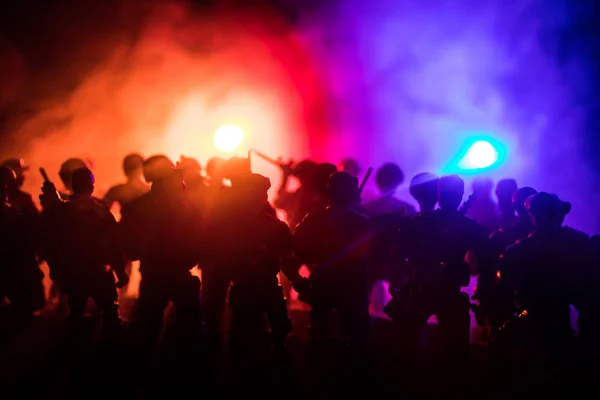 La policía antidisturbios da la señal de estar listo. Concepto de poder gubernamental. Policía en acción. Fuma sobre un fondo oscuro con luces. Sirenas intermitentes azules rojas . —  Fotos de Stock