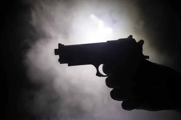 Pistola a mano maschile su sfondo nero con luci posteriori toniche fumo — Foto Stock