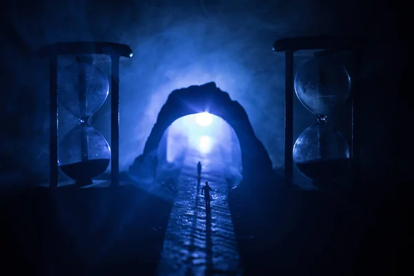 Η ιδέα του χρόνου. Σιλουέτα ενός άνδρα που στέκεται ανάμεσα σε κλεψύδρα με καπνό και φώτα σε σκούρο φόντο. Σουρεαλιστική διακοσμημένη εικόνα — Φωτογραφία Αρχείου