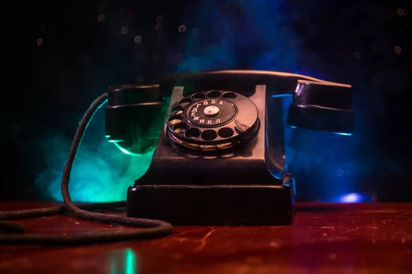 Telefone preto velho na tábua de madeira velha com arte fundo escuro com nevoeiro e luz tonificada. espaço vazio — Fotografia de Stock