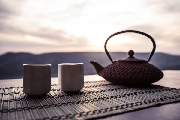 茶的概念。日本茶道文化东饮。茶壶和杯子在桌子上与竹叶在日落 — 图库照片