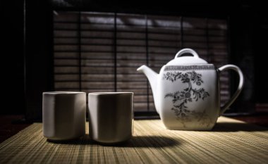 Çay konsepti. Japon çay töreni kültür doğu içecek. Gün batımında bambu yaprakları ile masada çaydanlık ve bardak