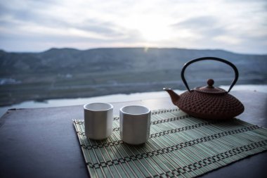 Çay konsepti. Japon çay töreni kültür doğu içecek. Gün batımında bambu yaprakları ile masada çaydanlık ve bardak