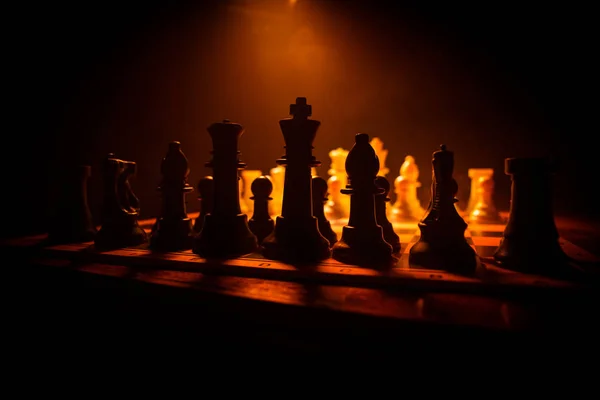Hra na šachovnici s obchodními nápady a konkurencí. Šachové postavy na tmavém pozadí s kouřem a mlhou. — Stock fotografie