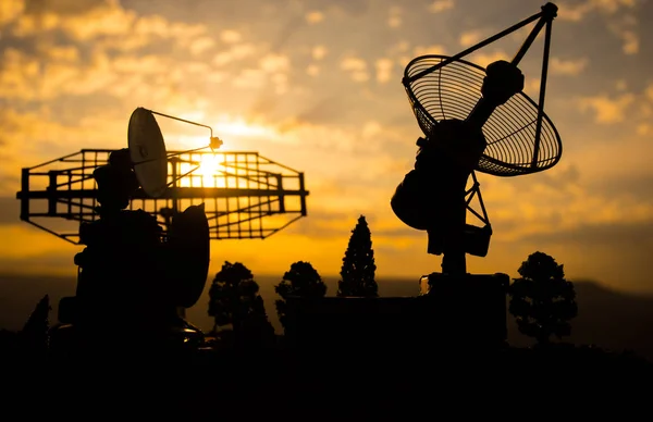 Силуэты спутниковых антенн или антенн против закатного неба. Космонавтика . — стоковое фото
