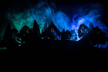 Geceleri ormanda bir hayaletin olduğu eski bir ev ya da sis içinde terk edilmiş bir korku evi. Ölü ağaç ormanındaki eski mistik bina. Geceleri aylı ağaçlar. Gerçeküstü ışıklar. Korku Cadılar Bayramı konsepti