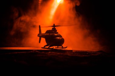 Askeri helikopter çatışma bölgesinden uçmaya hazır silüeti. Gece görüntüleri çöl sisli tonda sırt ile başlayarak helikopter ile dekore edilmiştir. Seçici odak.
