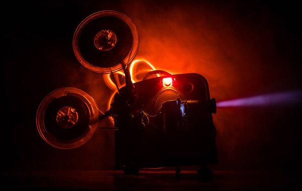 Old vintage movie projector on a dark background with fog and light. Concept of film-making.