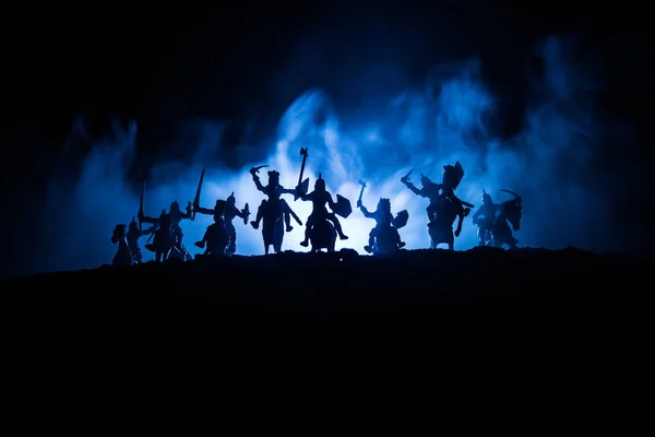 Escena de batalla medieval con caballería e infantería. Siluetas de figuras como objetos separados, lucha entre guerreros sobre fondo nebuloso tonificado oscuro con castillo medieval . — Foto de Stock