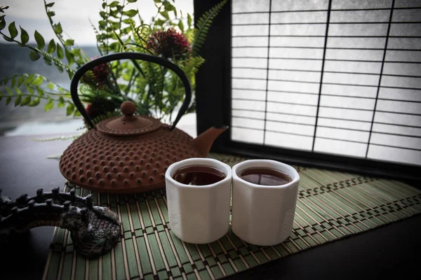 Tea concept. Japanese tea ceremony culture east beverage. Teapot and cups on table with bamboo leaves on sunset