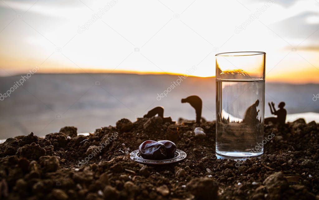 Water and dates. Iftar is the evening meal. View of decoration Ramadan Kareem holiday on sand. Festive greeting card, invitation for Muslim holyday.