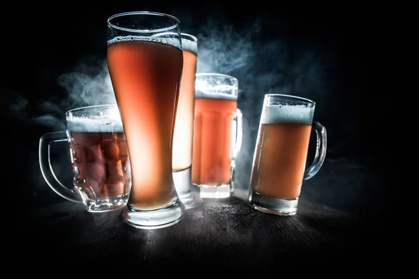 Concepto creativo. Vasos de cerveza sobre mesa de madera en fondo nebuloso tonificado oscuro . —  Fotos de Stock