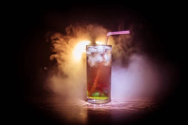 Коктейльное стекло брызгает на темном дымчатом фоне или красочный коктейль в стекле. Развлечения в клубе. Смешанный свет . — стоковое фото