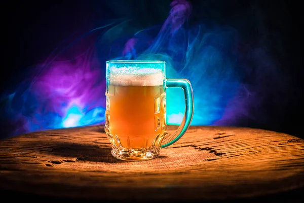 Concepto creativo. Vasos de cerveza sobre mesa de madera en fondo nebuloso tonificado oscuro . — Foto de Stock