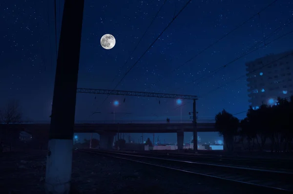 Estrada de ferro durante a noite sob lua cheia. Bela paisagem noturna com ponte sobre a ferrovia — Fotografia de Stock