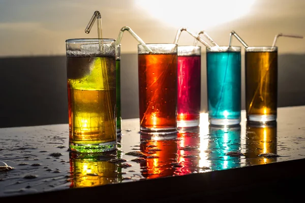 Cooling summer drink concept. Cocktail glasses splashing on sunset. Close up wet glass of cold drink on the terrace. — Stock Photo, Image