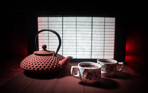 Tea concept. Japanese tea ceremony culture east beverage. Teapot and cups on table with bamboo leaves on sunset — Stock Photo, Image