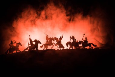 Medieval battle scene with cavalry and infantry. Silhouettes of figures as separate objects, fight between warriors on dark toned foggy background with medieval castle. clipart