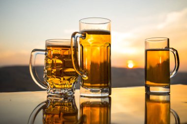 Gün batımında sahilde bir bardak bira. Soğutma yaz içki konsepti. Güneş ışığı Arka Plan Bokeh ile Draught Bira Bir Bardak Close Up