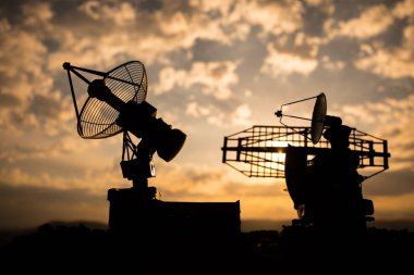 Gün batımı gökyüzüne karşı uydu antenleri veya radyo antenleri siluetleri. Uzay gözlemevi.