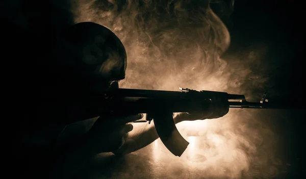 Silueta de hombre con rifle de asalto listo para atacar sobre fondo de niebla tonificado oscuro o bandido peligroso sosteniendo la pistola en la mano . —  Fotos de Stock