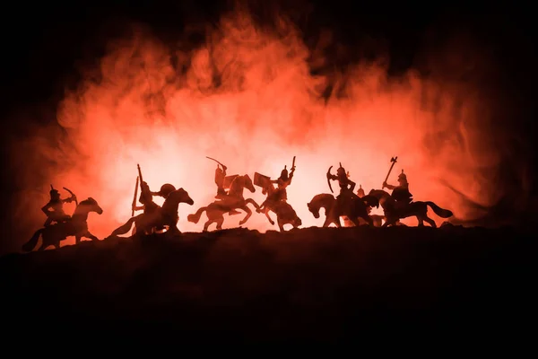 Escena de batalla medieval con caballería e infantería. Siluetas de figuras como objetos separados, lucha entre guerreros sobre fondo nebuloso tonificado oscuro con castillo medieval . — Foto de Stock