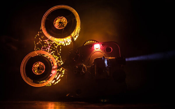 Old vintage movie projector on a dark background with fog and light. Concept of film-making.