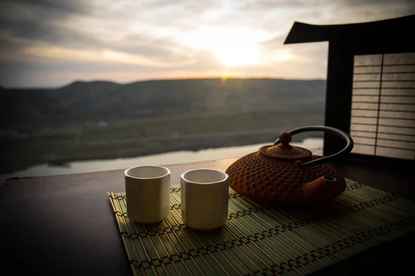 茶的概念。日本茶道文化东饮。茶壶和杯子在桌子上与竹叶在日落 — 图库照片