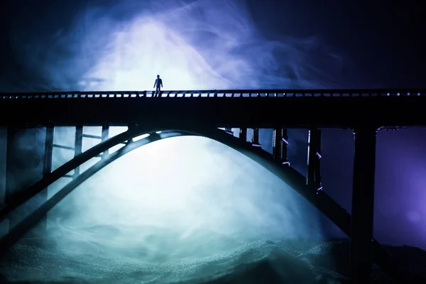 Художнє оздоблення. Силует потужного металевого моста вночі з туманним підсвічуванням. Силует людини, що стоїть на мосту . — стокове фото