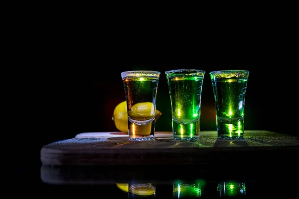 Concetto da club drink. Gustoso cocktail di bevande alcoliche tequila con lime e sale su uno sfondo scuro vibrante o bicchieri con tequila in un bar — Foto Stock