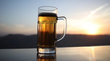 Gün batımında sahilde bira kadehleri. Soğutma yaz içki konsepti. Güneş ışığı Arka Plan, Yumuşak Odak Bokeh ile Draught Bira Bir Bardak Close Up