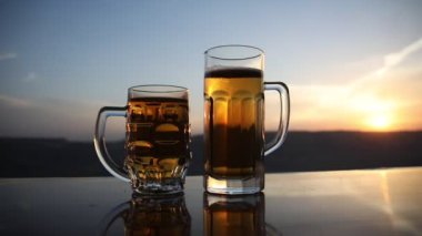 Gün batımında sahilde bira kadehleri. Soğutma yaz içki konsepti. Güneş ışığı Arka Plan, Yumuşak Odak Bokeh ile Draught Bira Bir Bardak Close Up