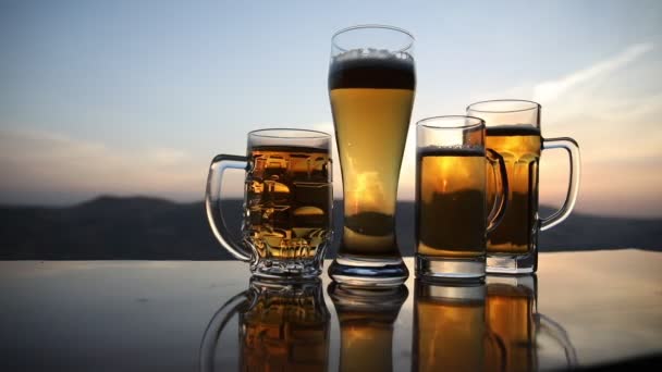 Lunettes de bière sur une plage au coucher du soleil. Concept de boisson rafraîchissante d'été. Gros plan d'un verre de bière tirée d'eau avec le Bokeh du fond de lumière du soleil, mise au point douce 