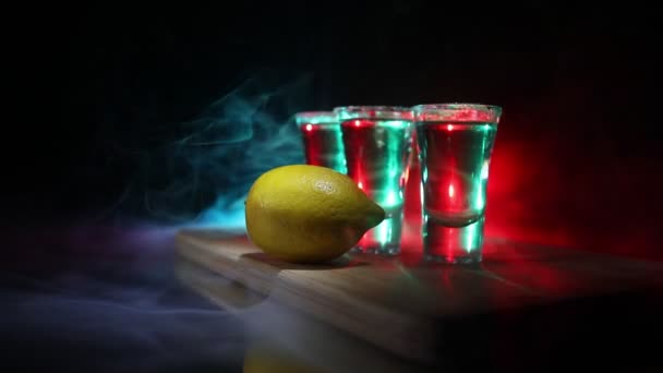 クラブドリンクコンセプト おいしいアルコールは バーでテキーラと鮮やかな暗い背景やメガネにライムと塩とカクテルテキーラを飲みます 選択フォーカス — ストック動画