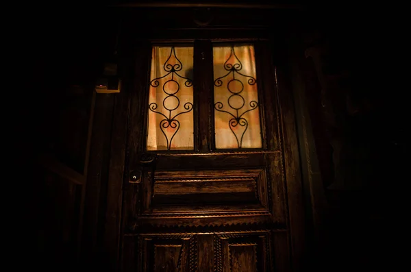 Sylwetka nieznanego cienia figura na starych drewnianych drzwiach przez zamknięte szklane drzwi. Sylwetka człowieka przed oknem w nocy. — Zdjęcie stockowe