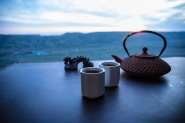 Çay konsepti. Japon çay töreni kültür doğu içecek. Gün batımında bambu yaprakları ile masada çaydanlık ve bardak