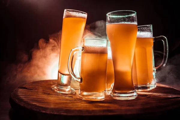 Concepto creativo. Vasos de cerveza sobre mesa de madera en fondo nebuloso tonificado oscuro . — Foto de Stock