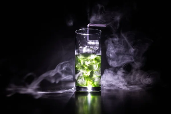 鸡尾酒杯溅在黑暗的色调烟雾背景或五颜六色的鸡尾酒在玻璃。派对俱乐部娱乐。混合光. — 图库照片