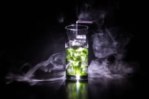 Cocktail glass splashing on dark toned smoky background or colorful cocktail in glass. Party club entertainment. Mixed light. — Stock Photo, Image