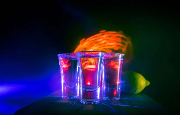 Concepto de bebida del club. Bebida alcohólica sabrosa cóctel de tequila con lima y sal sobre fondo oscuro vibrante o vasos con tequila en un bar — Foto de Stock