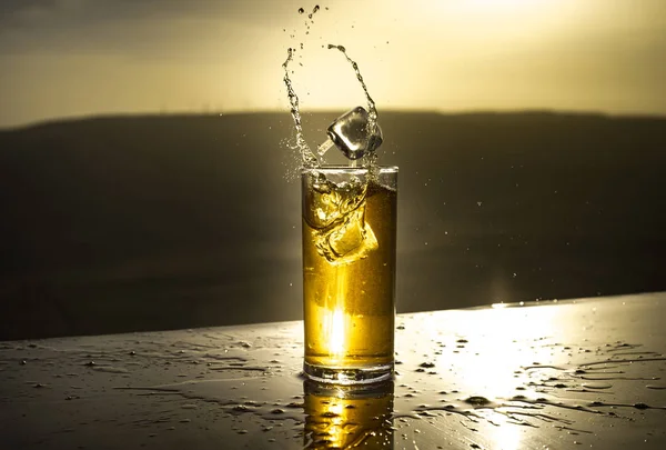 Svalkande sommardrink koncept. Cocktail glas stänk på solnedgången. Närbild våt glas kall dryck på terrassen. — Stockfoto
