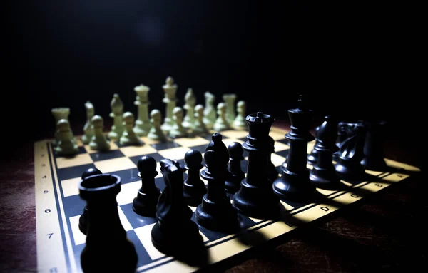 Hra na šachovnici s obchodními nápady a konkurencí. Šachové postavy na tmavém pozadí s kouřem a mlhou. — Stock fotografie