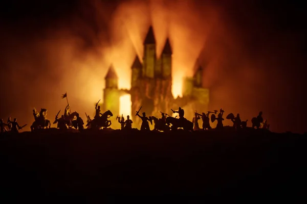 Cena de batalha medieval com cavalaria e infantaria. Silhuetas de figuras como objetos separados, luta entre guerreiros em fundo enevoado tonificado escuro com castelo medieval . — Fotografia de Stock