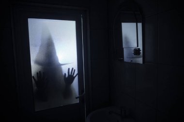 Horror silhouette of woman in window. Scary halloween concept Blurred silhouette of witch in bathroom. Selective focus clipart
