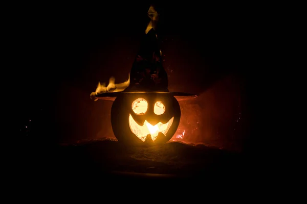 Concepto de Halloween. Sonrisa de Jack-o-linterna y ojos aterradores para la noche de fiesta. Vista de cerca de la calabaza de miedo con sombrero de bruja en el fondo de niebla oscura. Enfoque selectivo . —  Fotos de Stock