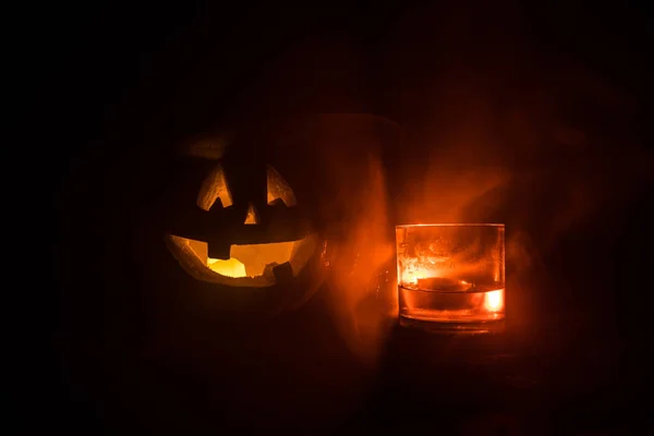 Dynia z rzeźbione twarz i szklankę whisky z lodem na ciemnym tle mglisty stonowanych z zombie. Urządzone. Selektywny fokus — Zdjęcie stockowe