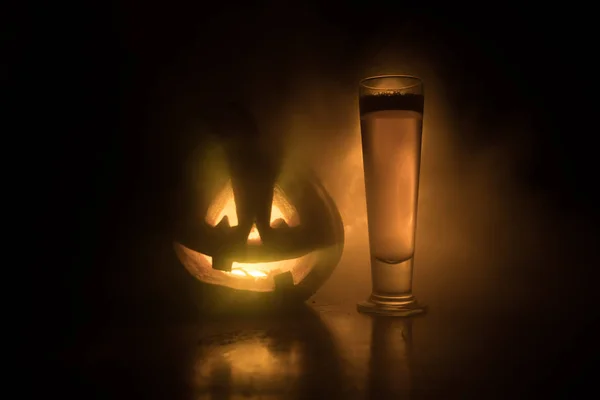 Glass of cold light beer with pumpkin on a wood background for Halloween. Glass of fresh beer and pumpkin on a dark toned foggy background